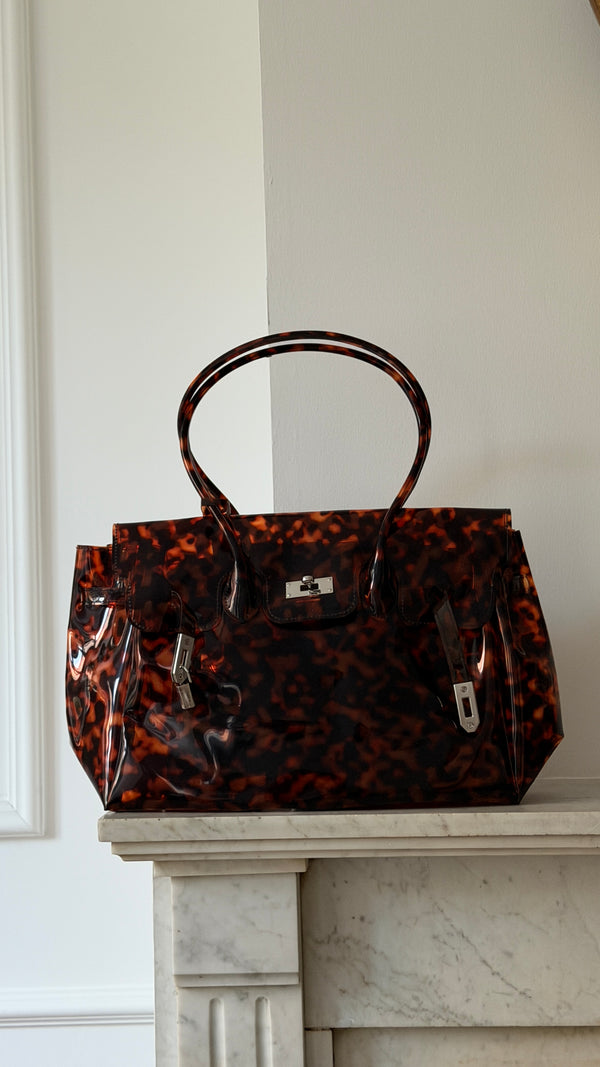 Le Sac Jelly Croco, coloris Ecaille vernie, pose sur une cheminee en marbre