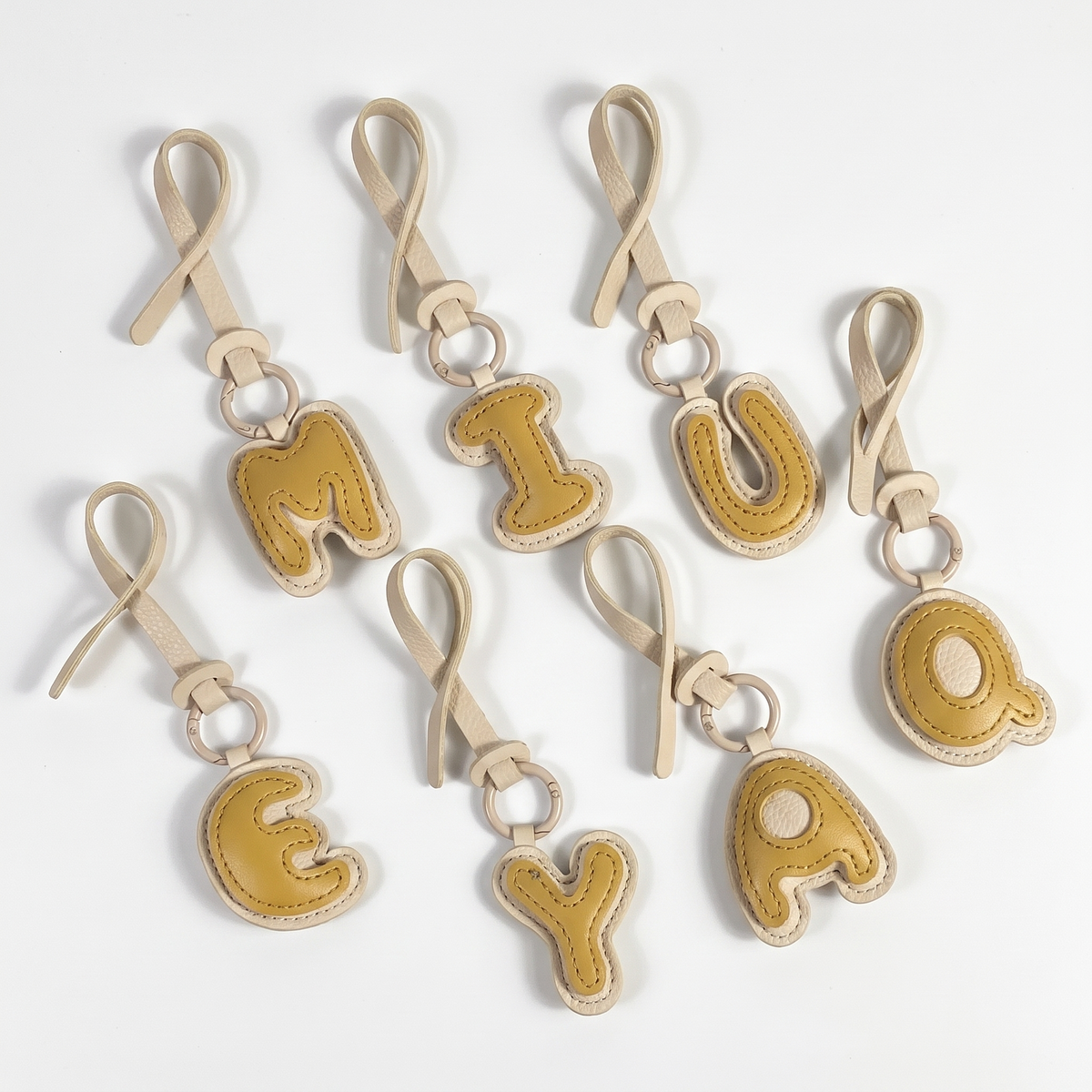 Charm lettre effet cuir matelasse et sa laniere assortie, sur fond blanc